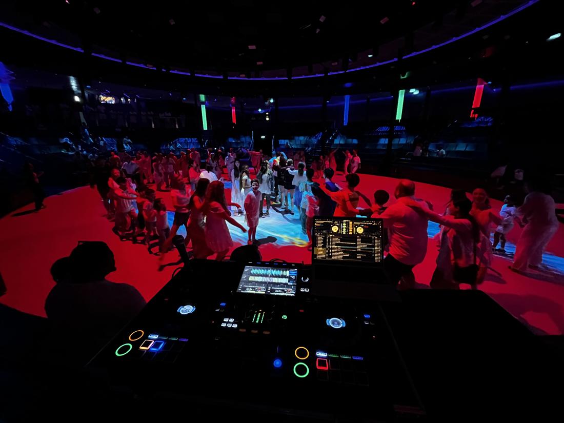 Kids dancing in a conga line under red party lights